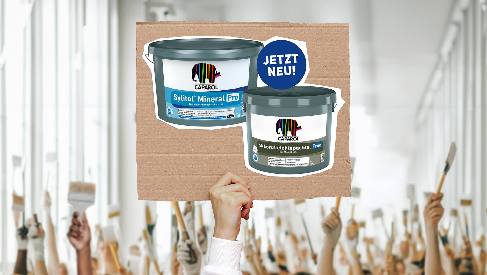 Hände halten Pappschild in die Luft. Darauf Sylitol® Mineral Pro und AkkordLeichtspachtel Free Gebinde mit Sticker und Aufschrift: Jetzt neu!