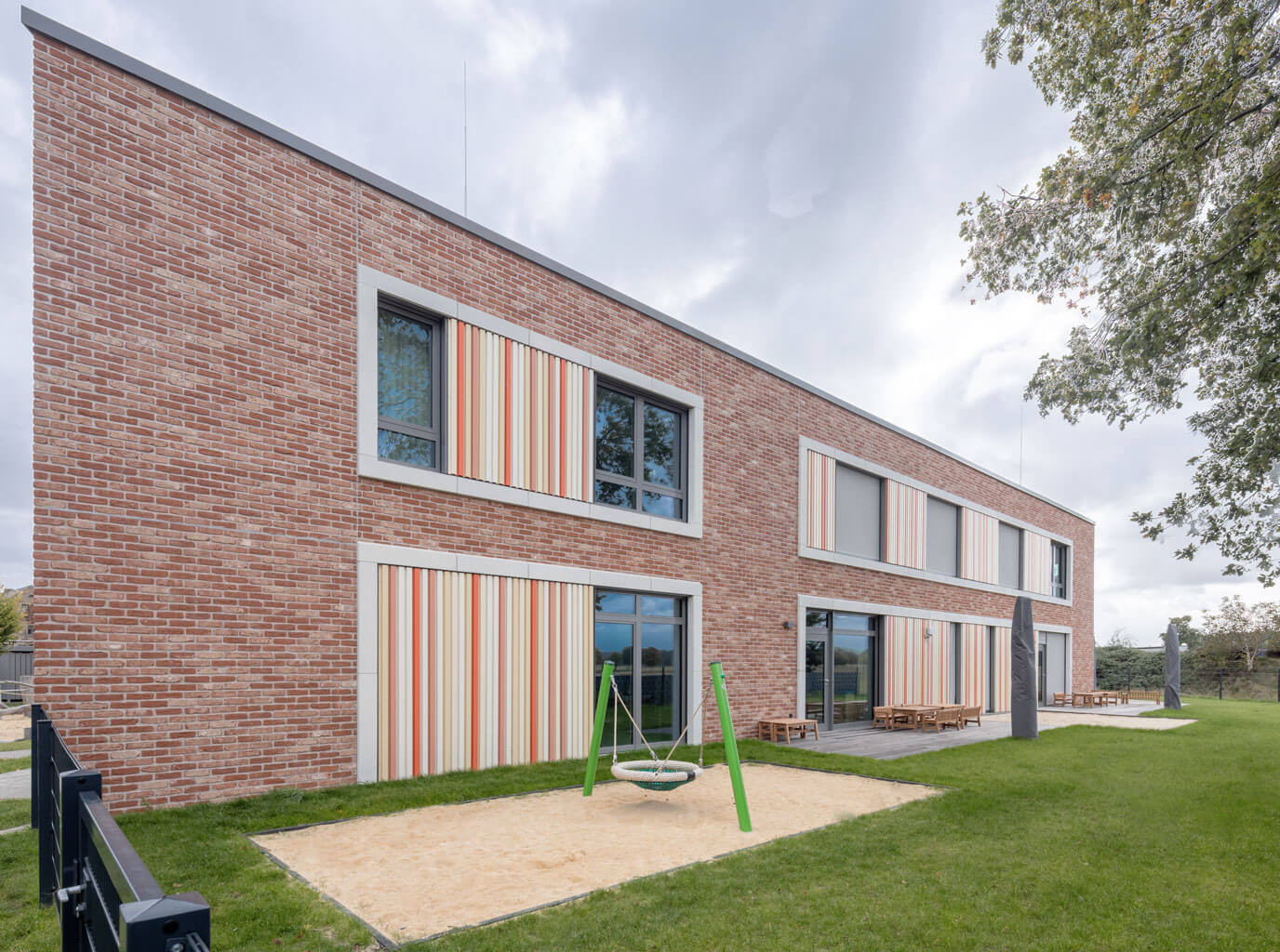 Spielbereich hinter der neuen Kindertagesstätte in Ralbitz-Rosenthal mit modernen Gebäuden im Hintergrund.