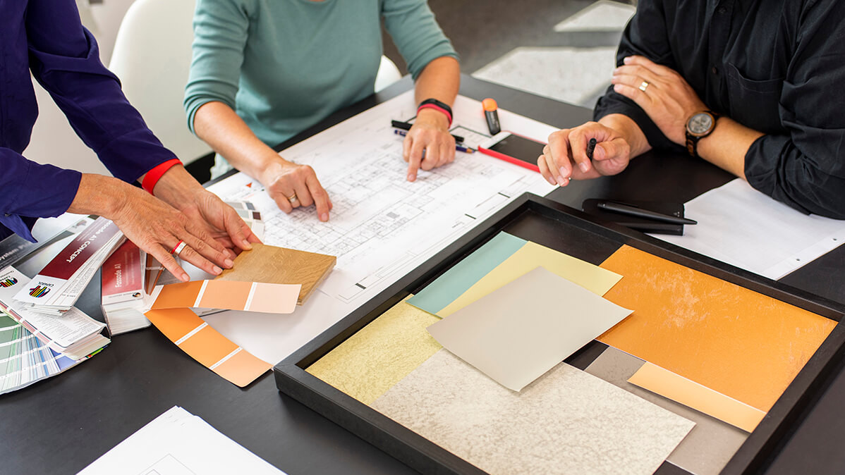 Frauen arbeiten an einem Tisch im Caparol Farbdesignstudio mit Farbmustern.