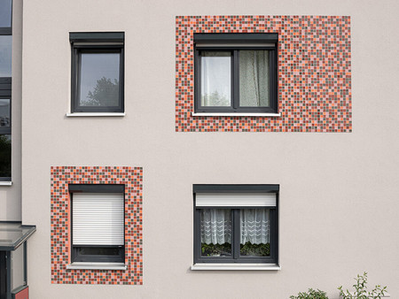 Farbige Glasmosaikflächen um einige Fenster akzentuieren die Fassadenfront
