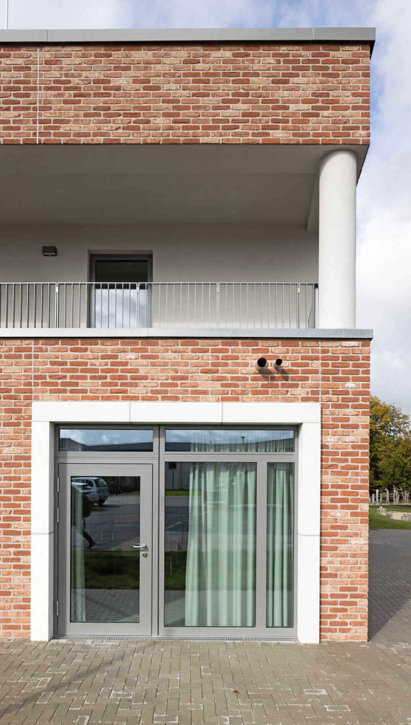 Nahaufnahme der Fassade des Kindergartenneubaus in Ralbitz-Rosenthal mit großen Fenstern und hellen, natürlichen Klinker-Wandflächen.