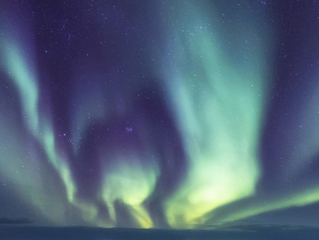 Kosmische Lichter erhellen den Nachthimmel in grünen und violetten Farben