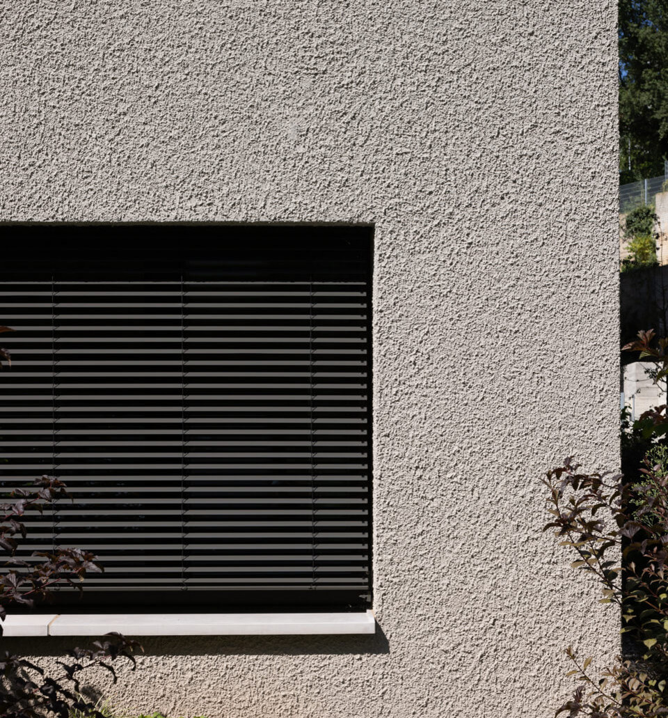Nahaufnahme der facettierten Außenwand mit Fenstern eines polygonalen Wohngebäudes in erdigen Grautönen, Stafflenbergstraße, Stuttgart.