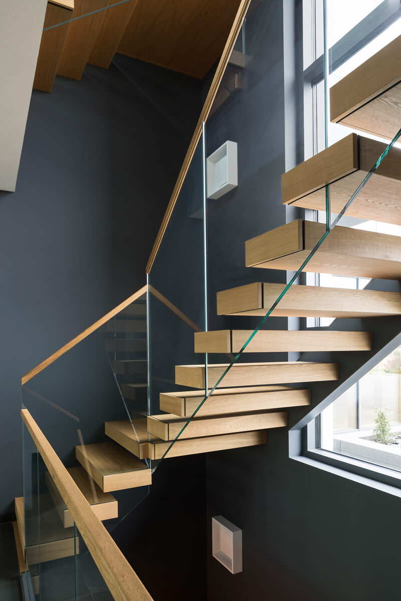 moderne verwinkelte Holztreppe mit Geländer aus Glas
