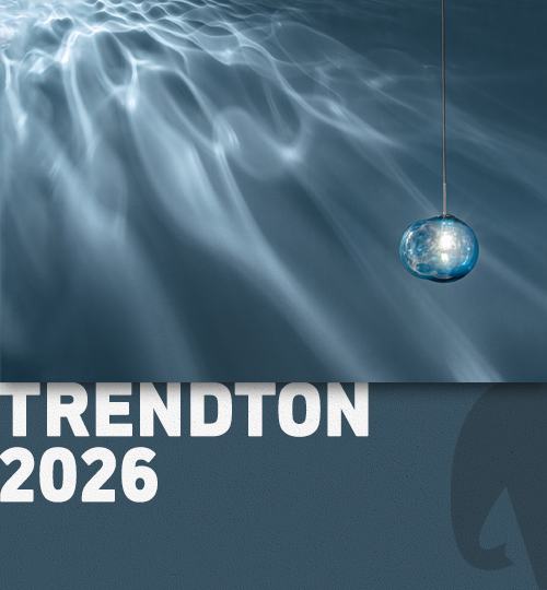 Eine grafische Darstellung mit einem sanften, blauen Wellenmuster im Hintergrund, über dem der Text "TRENDTON 2026" in großen, weißen Buchstaben platziert ist. Ein schimmerndes, kugelförmiges Lichtobjekt hängt oberhalb des Textes und verstärkt die moderne Ästhetik des Designs.