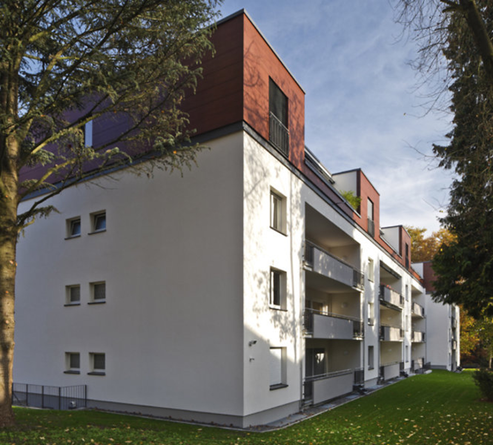 Seitenansicht der Fassade eines Mehrfamilienhauses im Grünen.