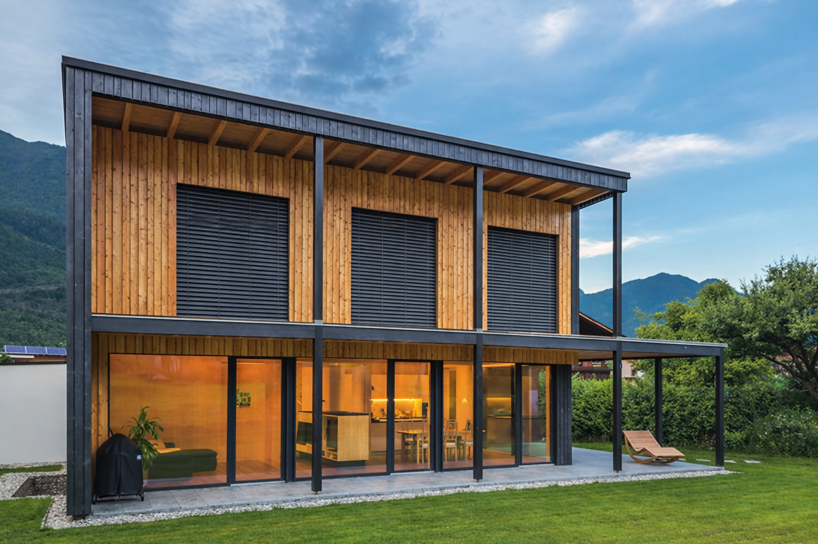 Modernes Haus Kneisl Ganahl mit Holzlasur in natürlicher Umgebung.