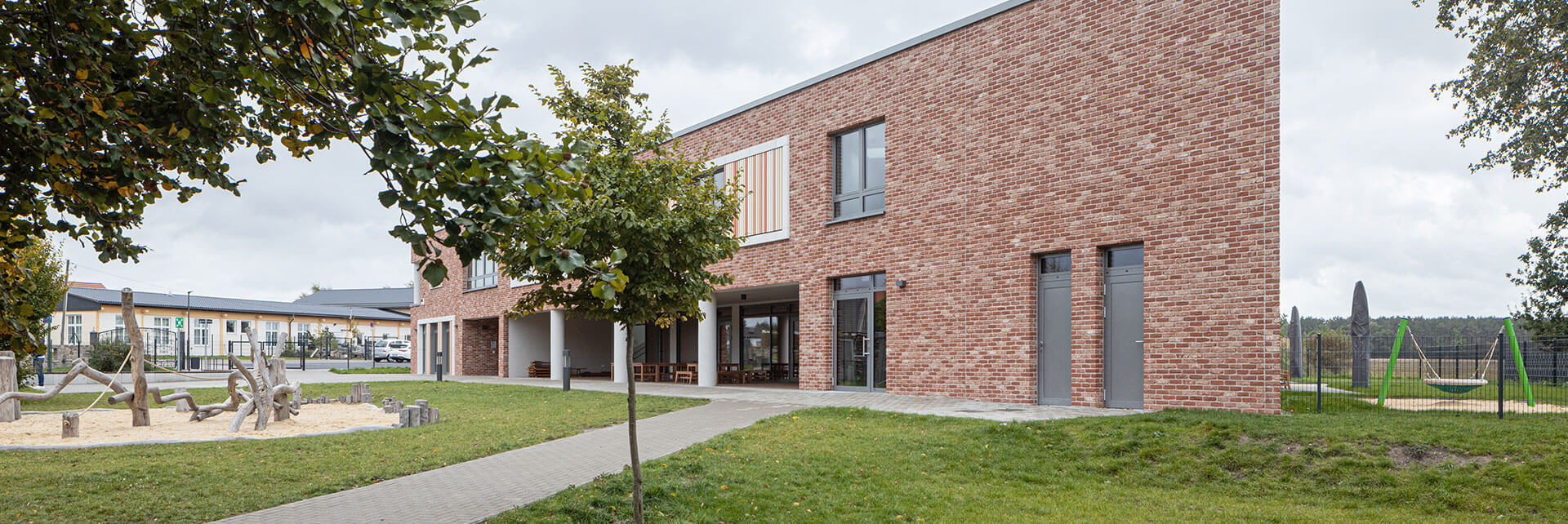 Spielbereich hinter der neuen Kindertagesstätte in Ralbitz-Rosenthal mit modernen Gebäuden im Hintergrund.