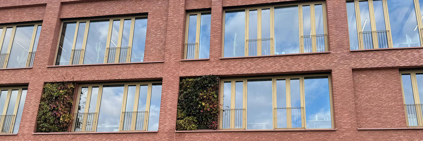 Fassade aus rötlichen Klinkerriemchen mit Fensterfront des Quartiers Q8 Neckarpark in Stuttgart mit blauem Himmel.