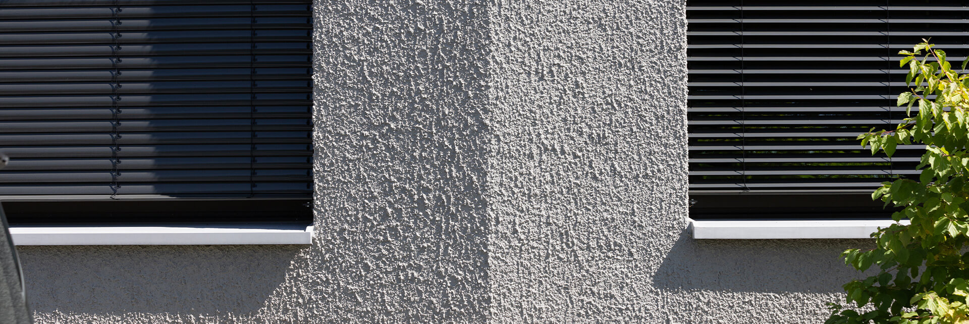 Nahaufnahme der facettierten Außenwand mit Fenstern eines polygonalen Wohngebäudes in erdigen Grautönen, Stafflenbergstraße, Stuttgart
