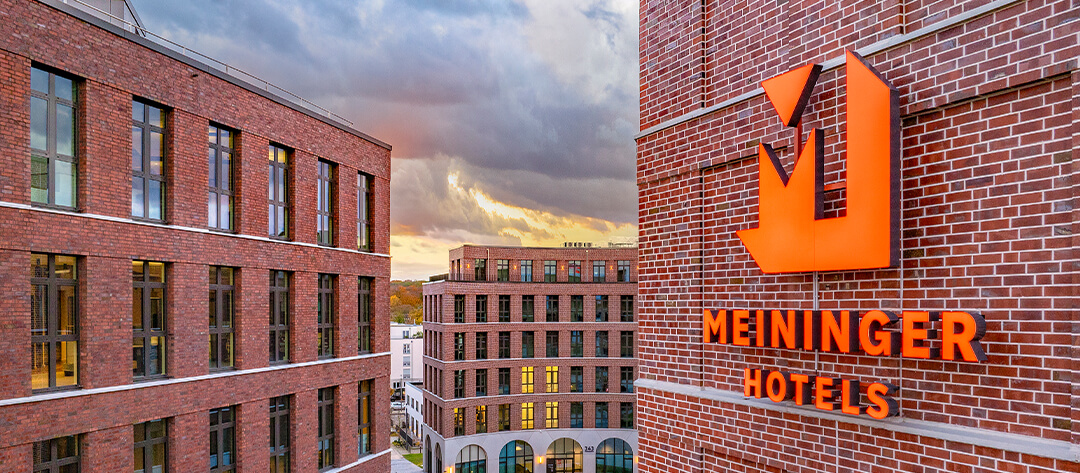 Detailaufnahme der dunklen Klinkerriemchen und Meiniger Hotel Logo am Gebäudeensemble Ovum