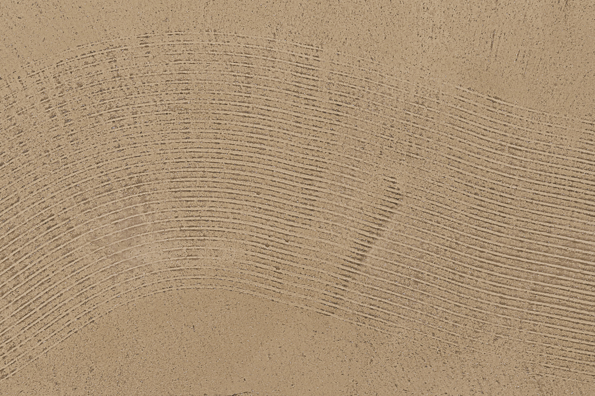 Textur einer sandfarbenen Oberfläche mit feinen Linien und Wellenmustern.