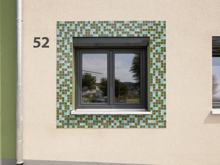Farbige Glasmosaikflächen um einige Fenster akzentuieren die Fassadenfront
