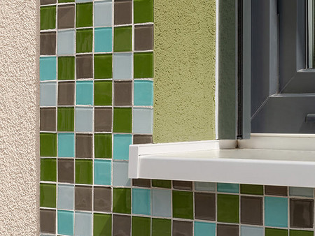 Die Mosaikflächen in Grün-Türkis-Hellblau werden durch die Fensterlaibungen im entsprechenden Farbton akzentuiert.
